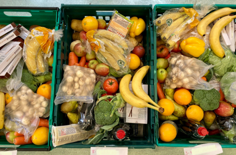 Green plastic crates filled with fruit, vegetables, and pantry items.