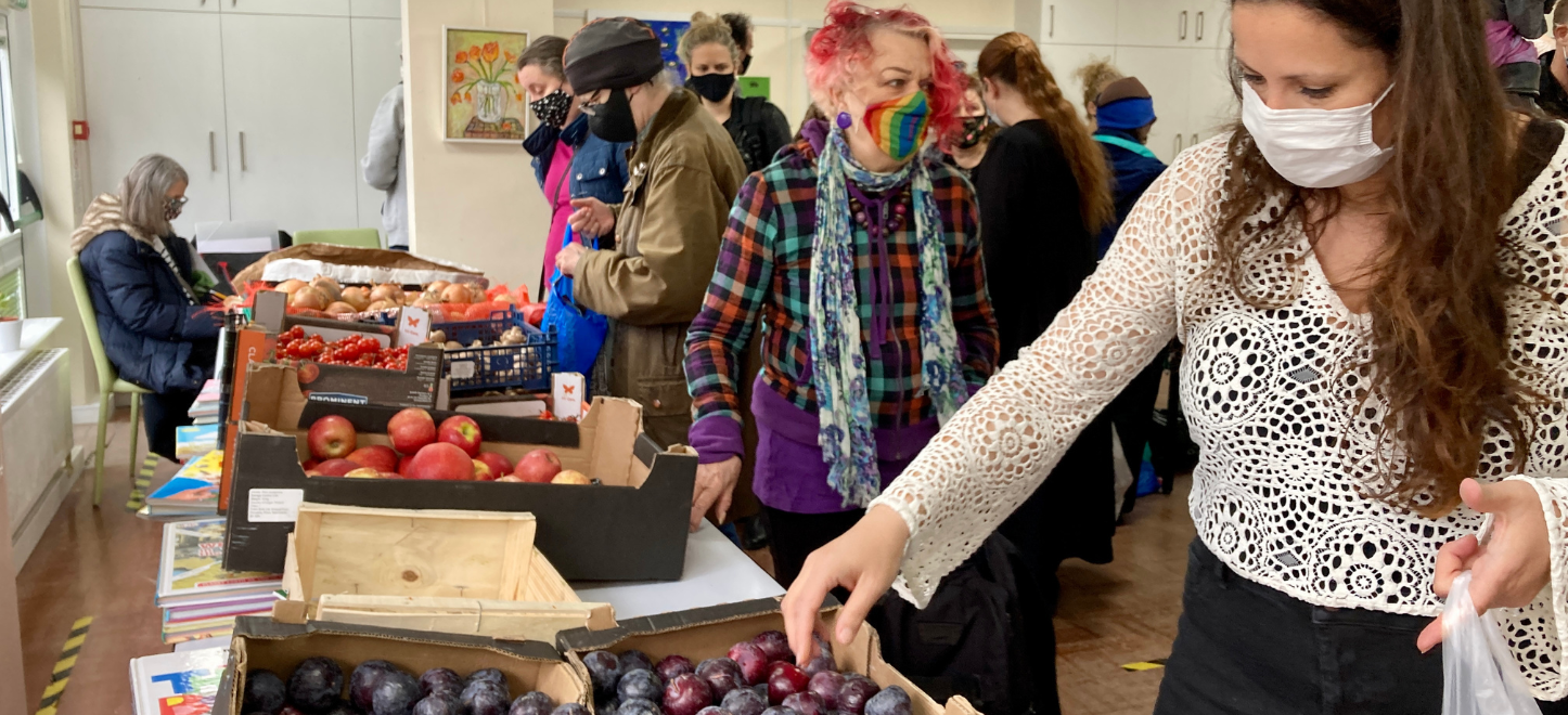 A gathering of people collecting food from crates.