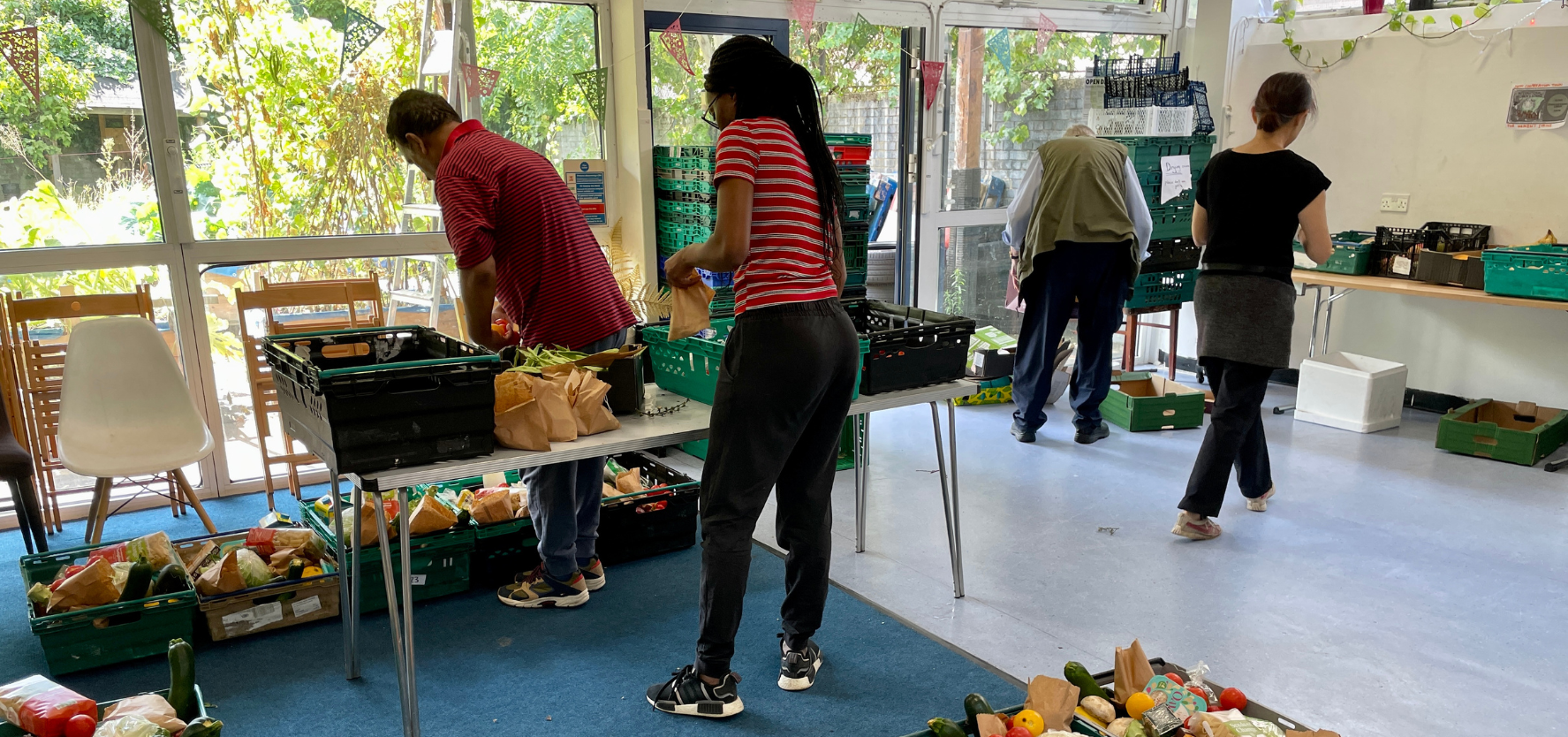 Four people are organising food into plastic crates. The crates are spread across tables and on the floor. Picture: Cooperation Town.