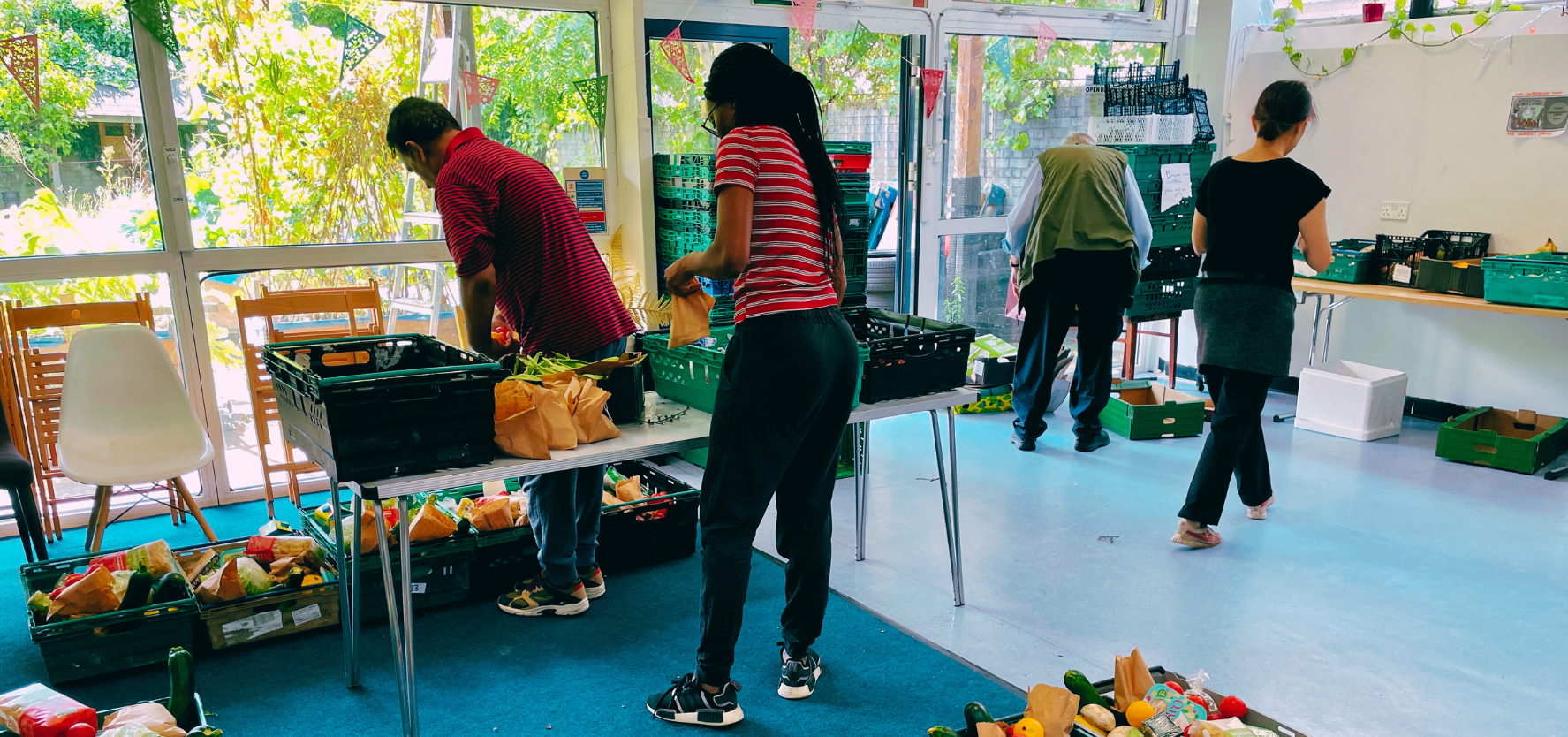 Four people are organising food into plastic crates. The crates are spread across tables and on the floor. Picture: Cooperation Town.