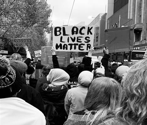 An image showing a crowd of people. One holds a sign saying Black Lives Matter